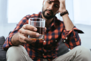 depressed man holding a glass with whiskey